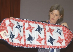 Tammy Stocks (upper right), Cooperative BaptistFellowship field personnel serving in Bucharest, Romania, displays a table runner produced by women at the Naomi Women’s Center, who learned to quilt after a CBF Heartland team made a visit last August. She made the presentation during a CBF Heartland meeting June 23 during the national CBF Annual Gathering in Greensboro, N.C. 