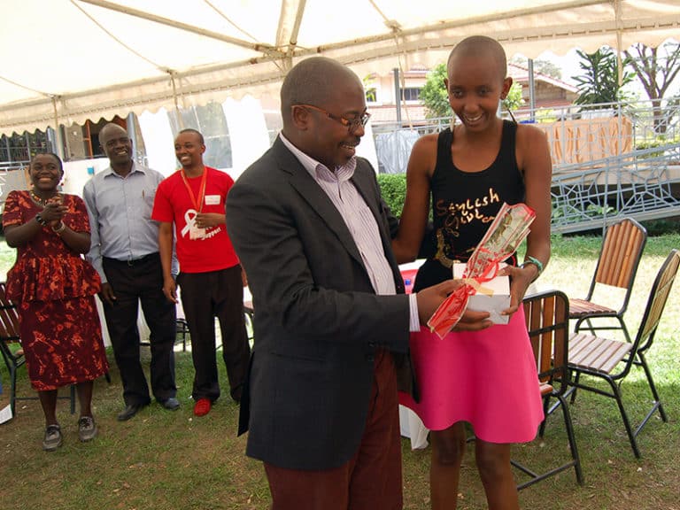 he Rev. Geoffrey Wanjala Munialo hands a rose and gift to Mary Mutua, a youth living with HIV, on Valentine’s Day in Nairobi, Kenya, on Feb. 14, 2017. RNS photo by Fredrick Nzwili