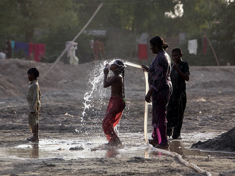 A woman gives her children a shower on a roadside during a heat wave in Lahore, Pakistan, on April 19, 2017. Photo courtesy of Reuters/Mohsin Raza