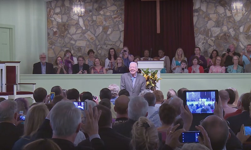 Guests take photos of former President Jimmy Carter at the beginning of a Sunday school class at Maranatha Baptist Church in Plains, Ga. Screenshot from YouTube
