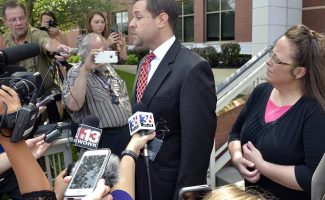 Rowan County Clerk Kim Davis, right, listens as her attorney Roger Gannam addresses the media on the steps of the U.S. District Court for the Eastern District of Kentucky in Covington on July 20, 2015. Davis, who has said she cannot issue marriage licenses to same-sex couples because it would violate her religious beliefs, is being sued by the American Civil Liberties Union on the behalf of two gay couples and two straight couples. (AP Photo/Timothy D. Easley)