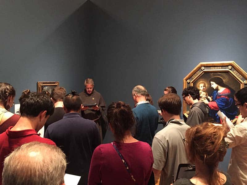 The Rev. Michael Martin, the Catholic chaplain at Duke University, leads a group of Catholic students in prayer before Carlo Dolci’s artwork at the Nasher Museum. RNS photo by Yonat Shimron