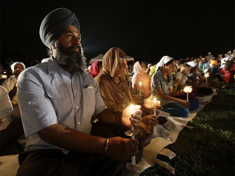 Raghu Vinder listens to speakers during a candlelight vigil in the parking lot of the Sikh Temple of Wisconsin on Aug. 5, 2013, in Oak Creek, Wis., marking the one-year anniversary of the shooting rampage in which a white supremacist killed six people. (AP Photo/Morry Gash)