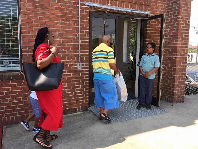 Kwame Cannon Jr., 11, right, greets worshippers at Faith Community Church in Greensboro, N.C., on May 13, 2018. The church shares space with several nonprofits in an old community center building. Three years ago solar panels were installed on the roof of the building. RNS photo by Yonat Shimron