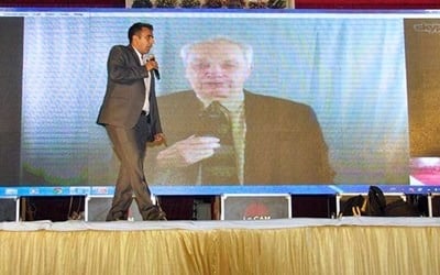 Evangelist Sammy Tippit, shown on screen in India, preaches an evangelistic message to a crowd of thousands, with live translation as he speaks from his office in San Antonio, Texas. Photo courtesy of Sammy Tippit Ministries