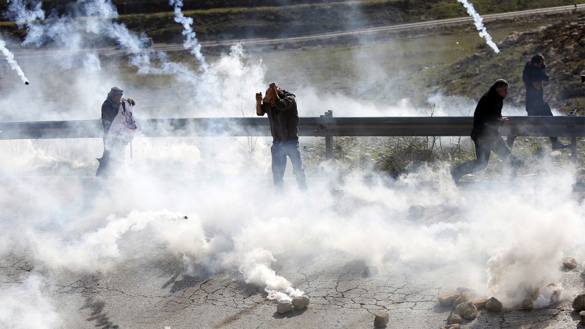 Palestinian demonstrators run from tear gas fired by Israeli troops during clashes following a demonstration in support of Palestinian prisoners in Nabi Saleh near the West Bank city of Ramallah, on Jan. 13, 2018. (AP Photo/Majdi Mohammed)