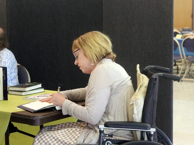 Karen Swallow Prior signs books after a speaking engagement at the National Presbyterian Church in Washington, D.C., on July 22, 2018. Prior used a wheelchair because she was struck by a bus two months before. RNS photo by Adelle M. Banks