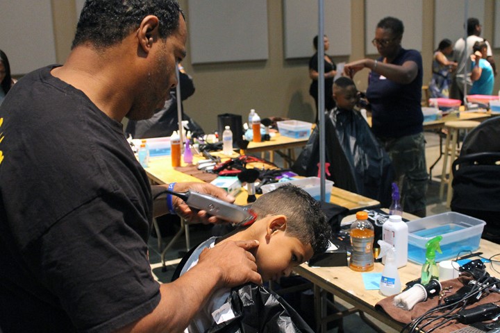 Stylist Tony Coursey cuts the hair of 4-year-old Trend Cooper, grandson of Pamela Jennings, at People’s Church in Oklahoma City on July 28, 2018. RNS photo by Bobby Ross Jr.