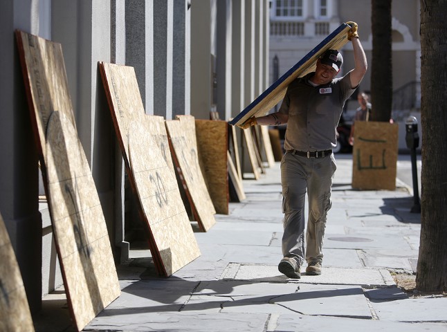 Preston Guiher carries a sheet of plywood as he prepares to board up a Wells Fargo bank in preparation for Hurricane Florence in downtown Charleston, S.C., on Sept. 11, 2018. (AP Photo/Mic Smith)