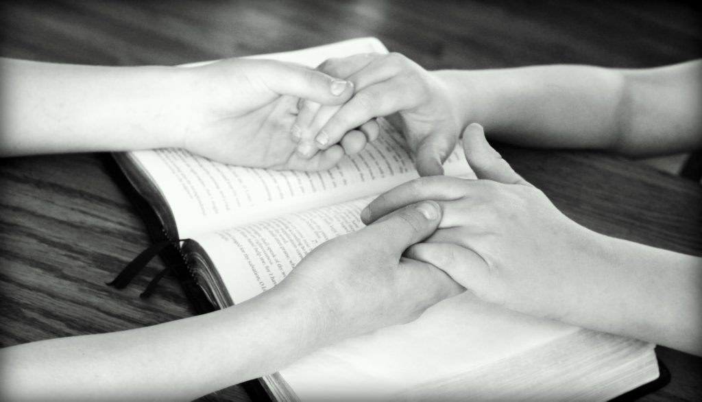 Holding hands over Bible