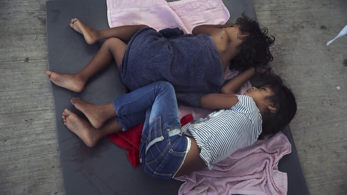 Migrant children sleep on a mattress