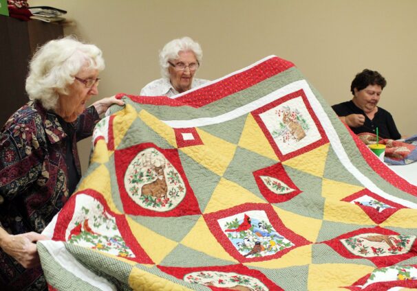sisters holding up quilt