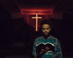 Man with Bible in front of cross