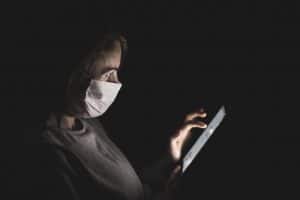 person with mask looking at tablet