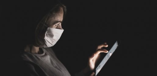 person with mask looking at tablet