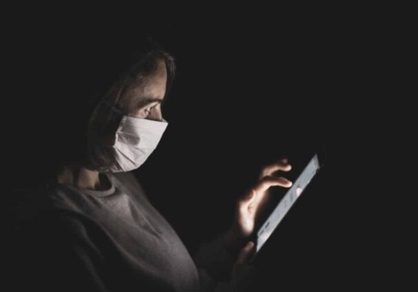 person with mask looking at tablet